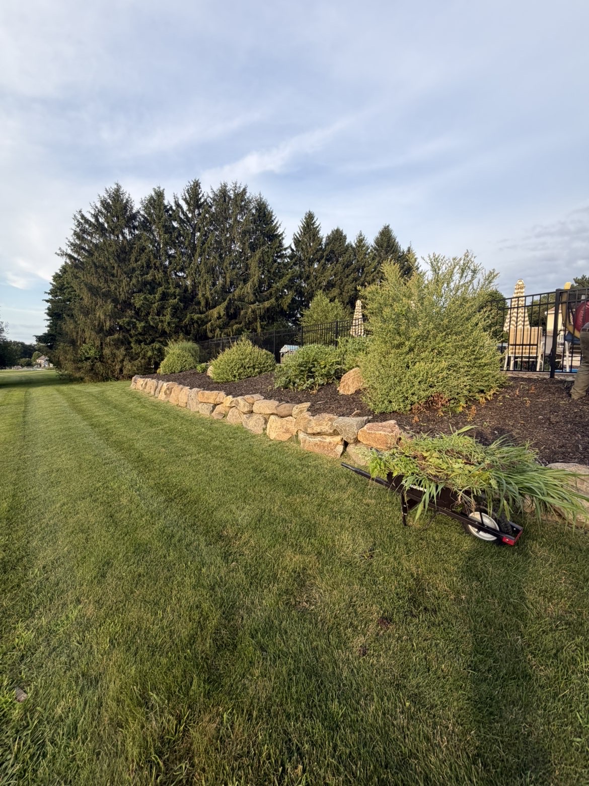 Fieldstone retaining wall with fresh mulch and planting beds